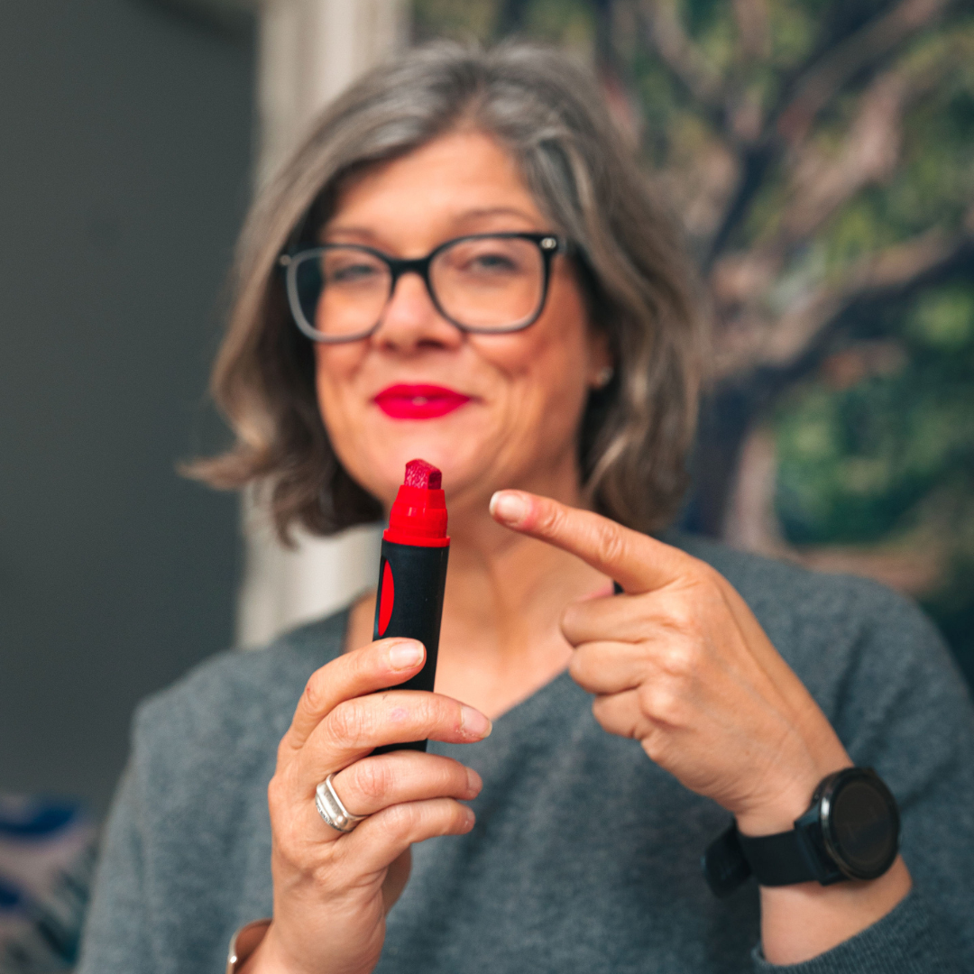 Photo of Kirsty Lewis, School of Facilitation pointing finger at Neuland BigOne wedge nib, red held in right hand. Sold in Inky Shop UK.