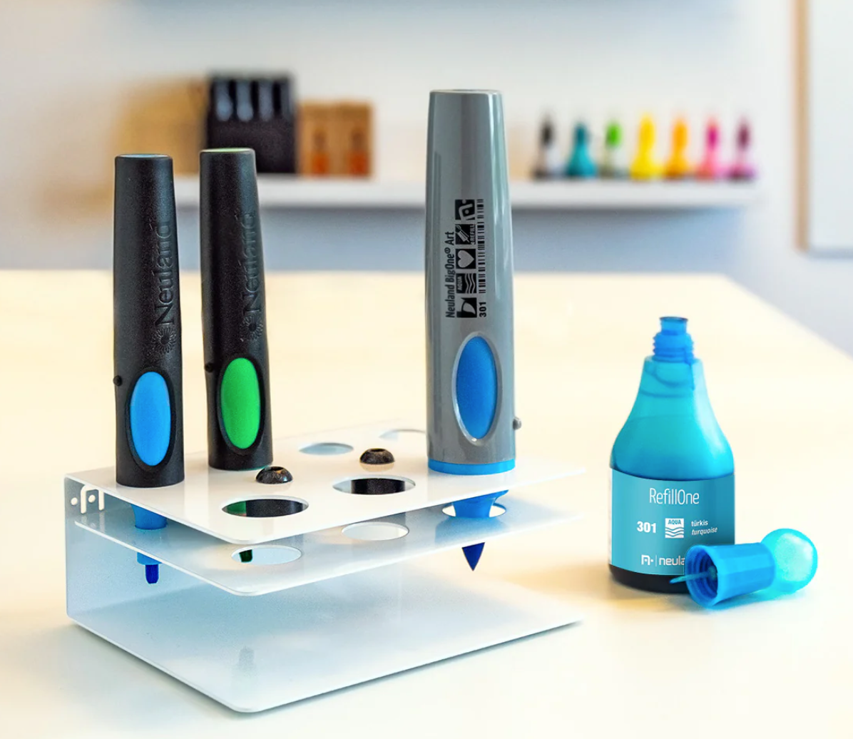 Neuland refill station with upturned Neuland markers and open bottle of refill ink