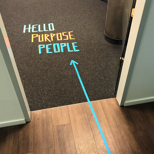 Neuland Floor Tape, blue and yellow writing, 'hello, purpose, people' wording taped to office floor. Tape  for art projects, meeting facilitation, graphic illustrations. Sold in UK via Inky Thinking GB Shop. Official Reseller. 