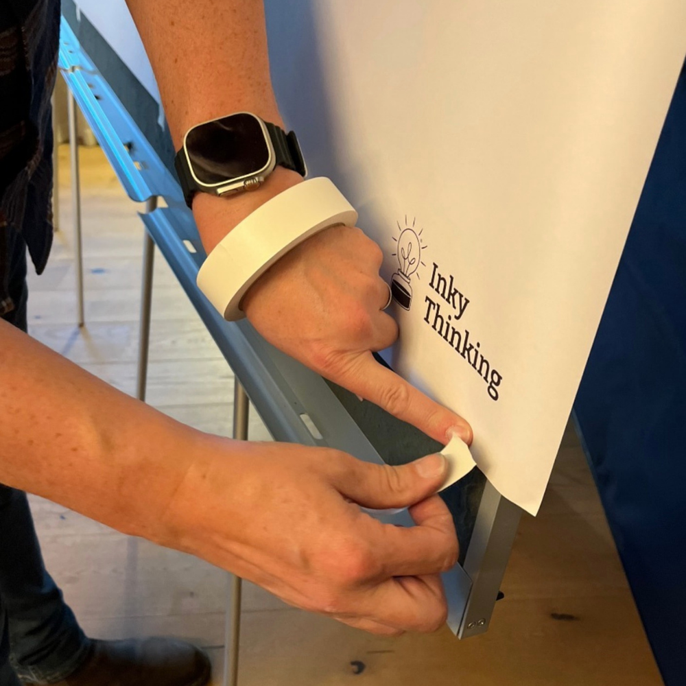 Person sticking paper to graphicwall with Artist Tape, safe tape for paper