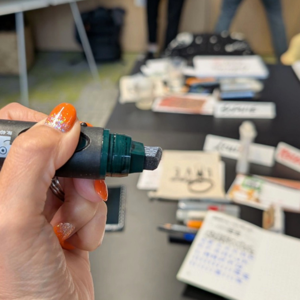 Hand holding a Neuland marker with a blurred background of a table with various items