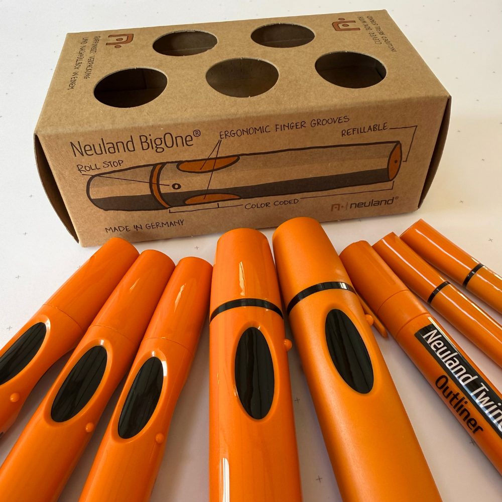 A set of Neuland refillable roller stop markers with black ink, arranged in front of their brown cardboard packaging box on a white surface.